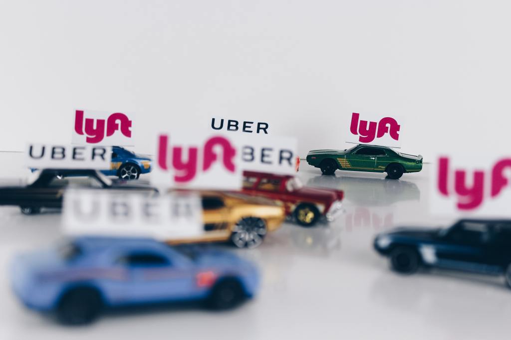 Toy cars with Uber and Lyft signs above them.