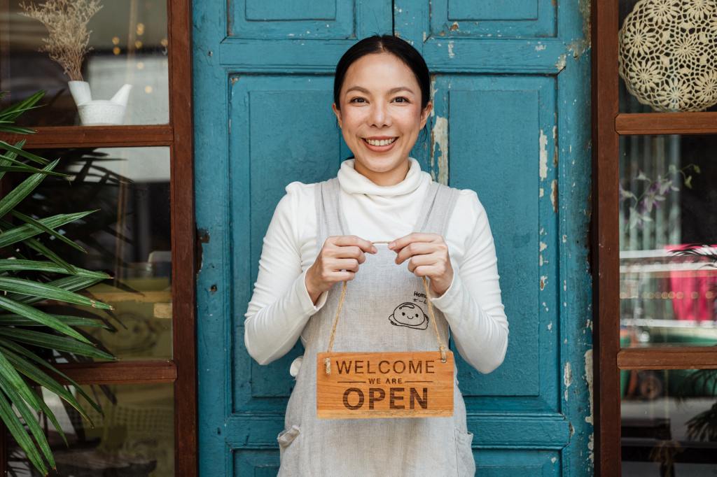 A woman holding a sign saying her business is open.
