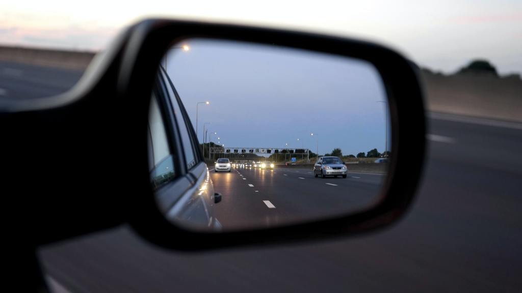 A rear-view mirror showing traffic behind a car.