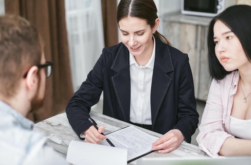 A sales person explaining paper work to two clients.